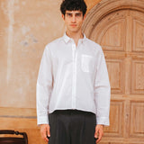 Man wearing a white shirt and black pants standing in front of a wooden door.